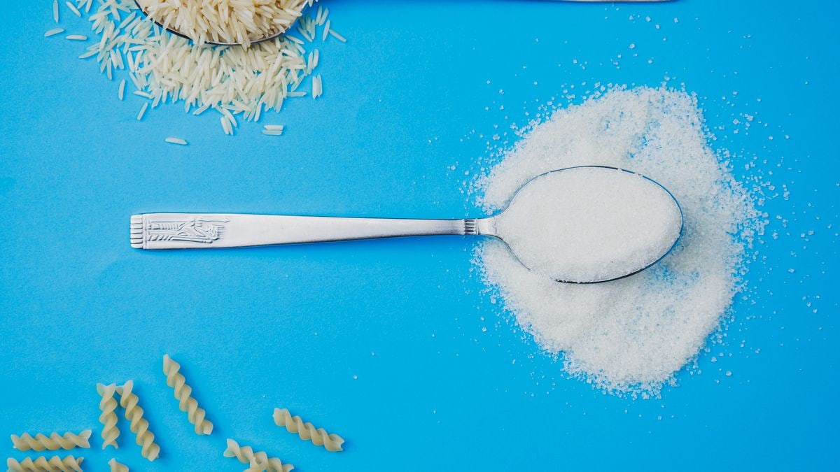 Sugar, rice, and pasta in spoons on a vivid blue surface. Perfect for food-related projects.